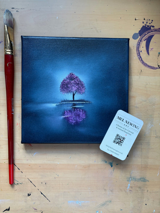 Canvas painting of a purple tree with a brush and artist's card on a wooden surface